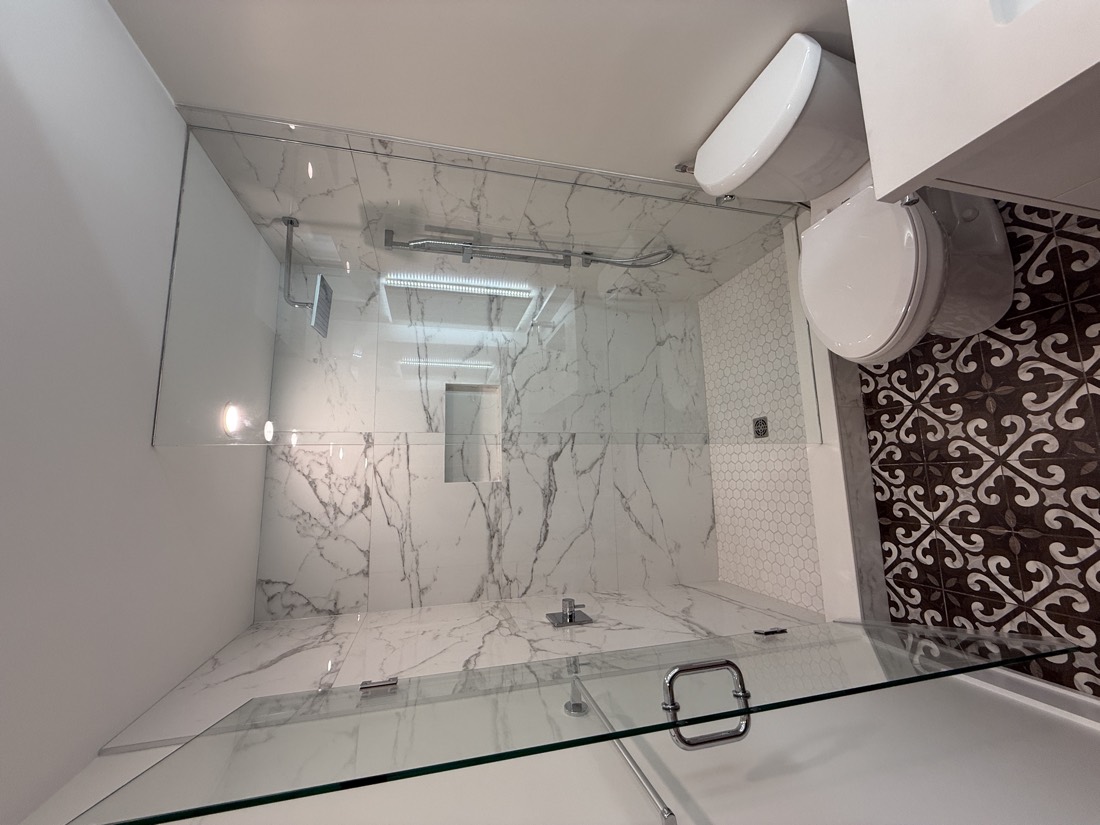 Marble shower with a dark patterned floor